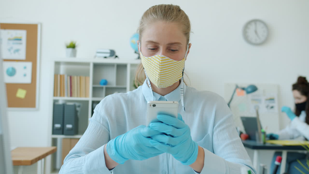 Woman in office using smartphone during pandemic
