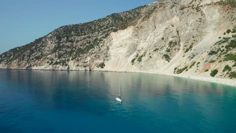 Aerial-view-Sailing-boat-on-emerald-water-over-scenic-Cliffs-at-Myrtos-beach,-Greece