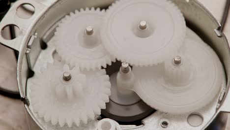 five plastic gears rotate in mutual mesh inside a small reduction gear