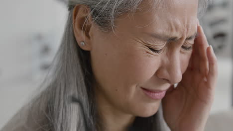 close up of middle aged woman having headache and touching her temples