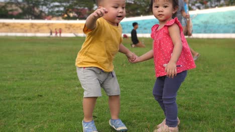 a toddler girl helps a toddler boy to get up