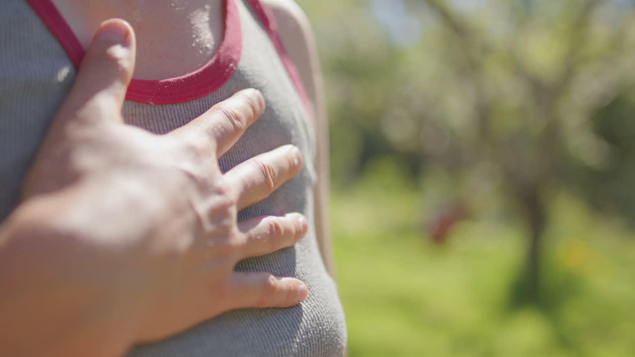 Woman meditates with hand on heart as hammock swings in tree of summer garden