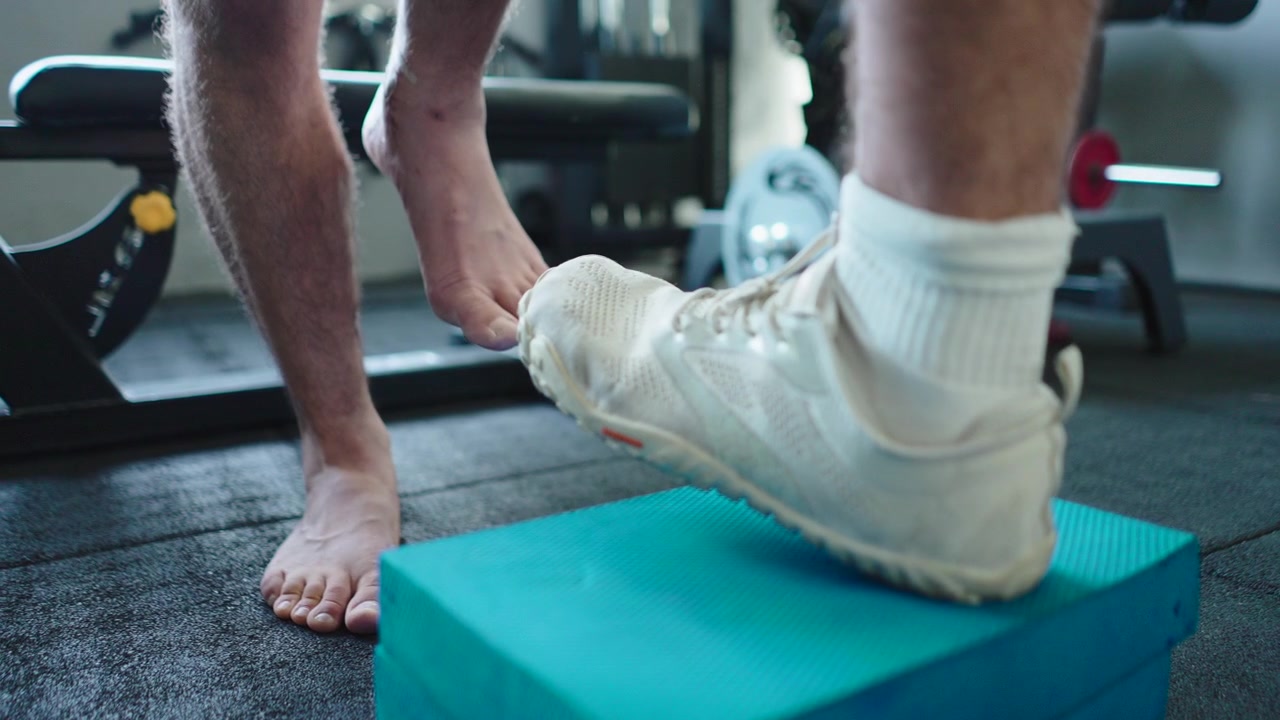 Person Performing Step-Up Exercise on Foam Block in Gym
