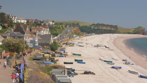 seafront of budleigh salterton. old houses, strolling people, colorful boats on the beach. jurassic coast, east devon area of outstanding natural beauty, england, uk.