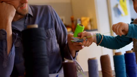 Father-and-son-holding-a-thread-roll-at-home-4k