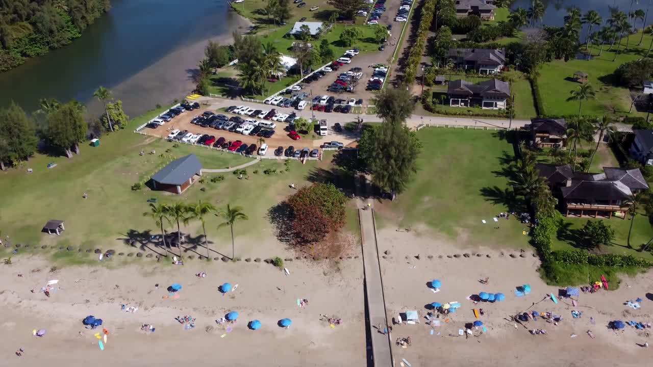 Aerial View of a Beautiful Beach with People, Parking Lot, and Pier