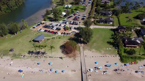 aerial view of a beautiful beach with people, parking lot, and pier