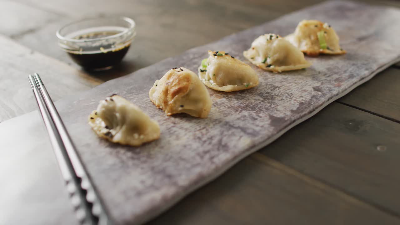 Komposisi piring dengan pangsit gyoza dan kecap asin dengan sumpit di latar belakang kayu