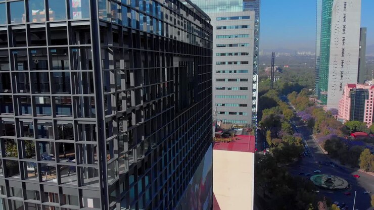 Paneo de dron de rascacielos en la Avenida Reforma de la Ciudad de México, entre árboles