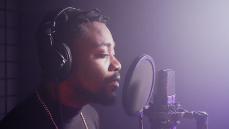 man singing into a microphone in a recording studio