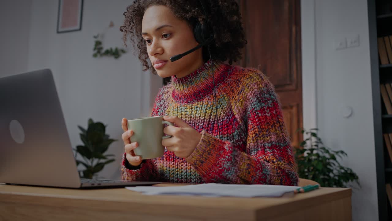 trabajo acogedor desde casa. joven dama afroamericana en auriculares escribiendo en portátil, trabajando desde casa, enfoque selectivo