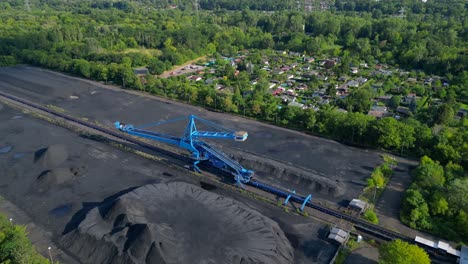 spreader reclaiming coal excavator at a coal terminal near residential area. magic aerial view flight fly reverse drone