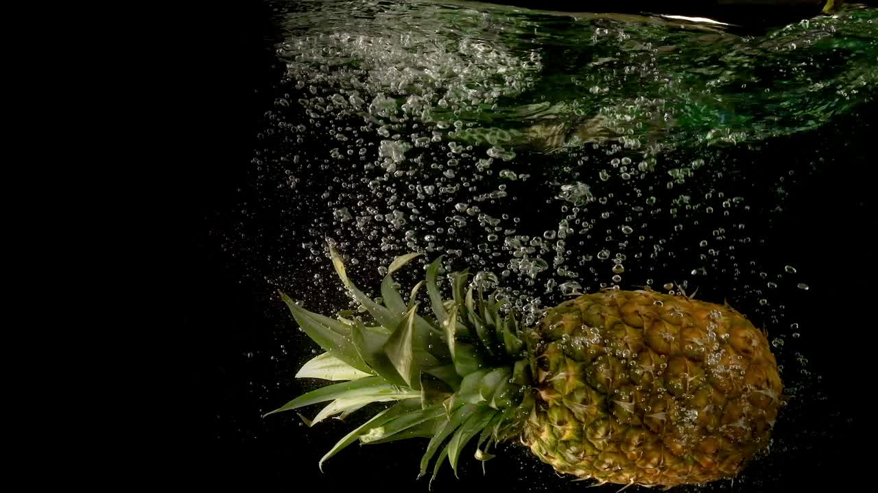 거품이 있는 은 어두운 물에 떨어지는 큰 성숙하고 맛있는 온 파인애플