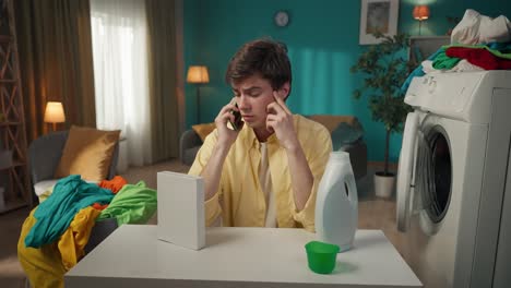 young man doing laundry and having a phone call