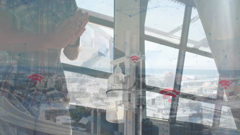 standing by window, person viewing animation of wi-fi symbols over cityscape