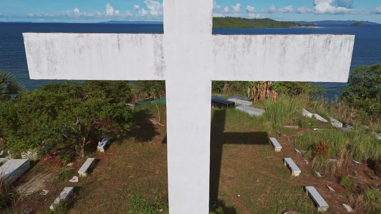 dolly pan abajo de cerca de una cruz cristiana blanca en un cementerio contra un cielo azul en las filipinas