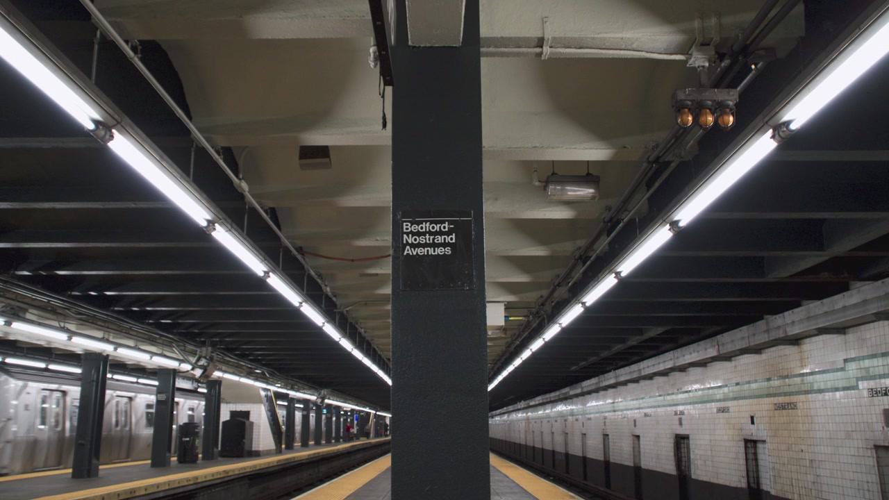 Etableringsbilde av et tog som forlater t-banestasjonen. Filmet ved Bedford-Nostrand i Brooklyn, New York