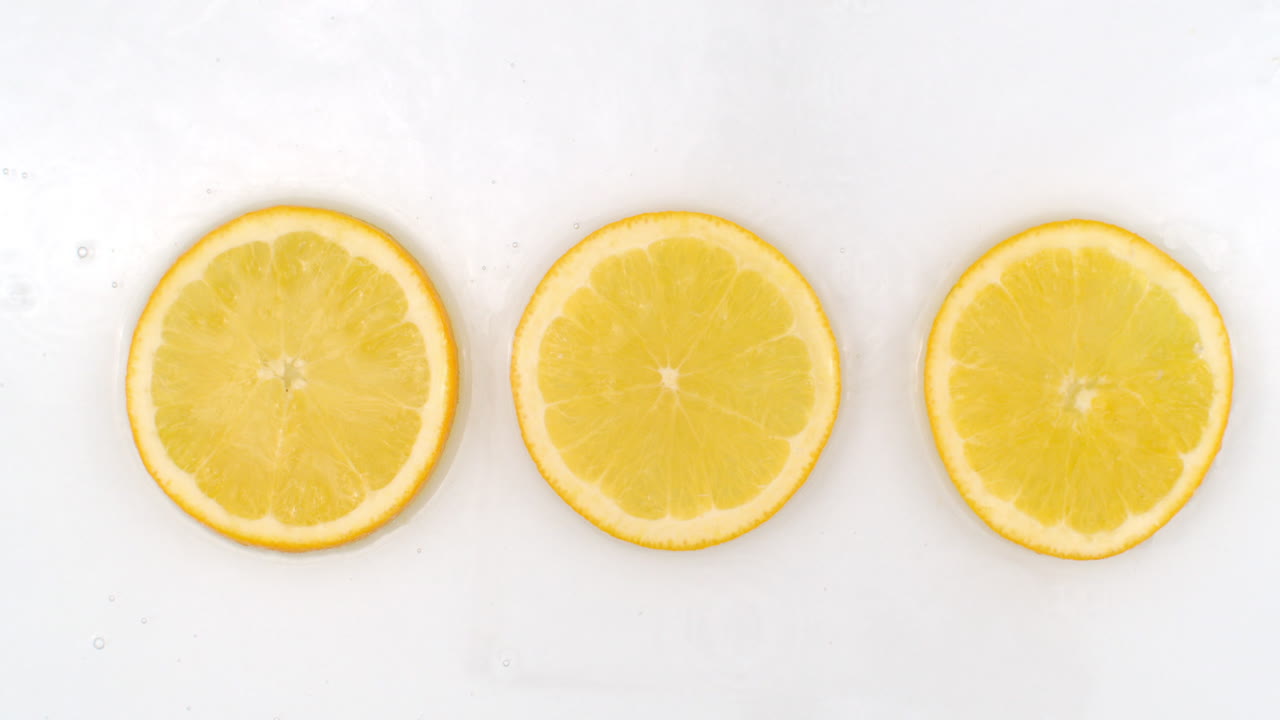 Three fresh lemon top view of water flowing on a white background.