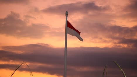 indonesian flag flying on a high pole against a dramatic evening sky