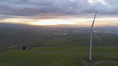 lonely wind turbine facing the sun setting with moody clouds