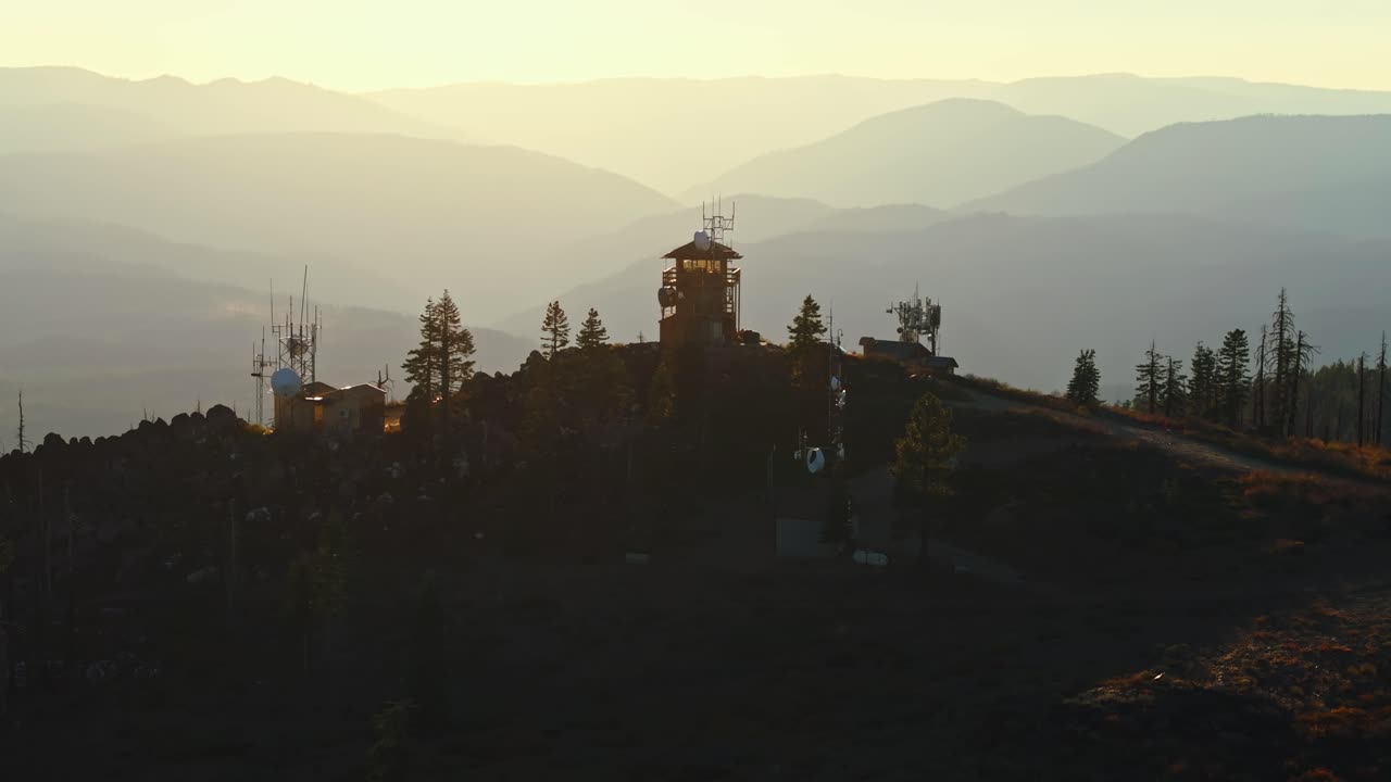 Sunlit fire lookout tower in California wilderness during sunset