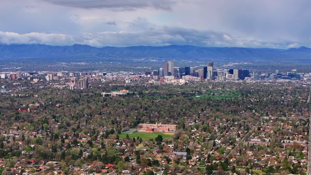 Front Range Denver Lowry Northfield Central Park Colorado aerial drone neighborhood apartment buildings sunny cloudy sky cloudy North High School cars cityscape skyscrapers forward pan up motion