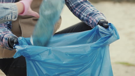 put plastic trash in a bag cleaning the park taking care of the environment