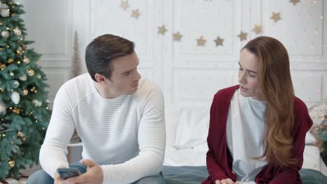 serious couple looking mobile phones in luxury bedroom.