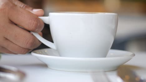 person holding a coffee cup in a cafe