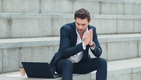 businessman typing on laptop at street. man in suit working outside office