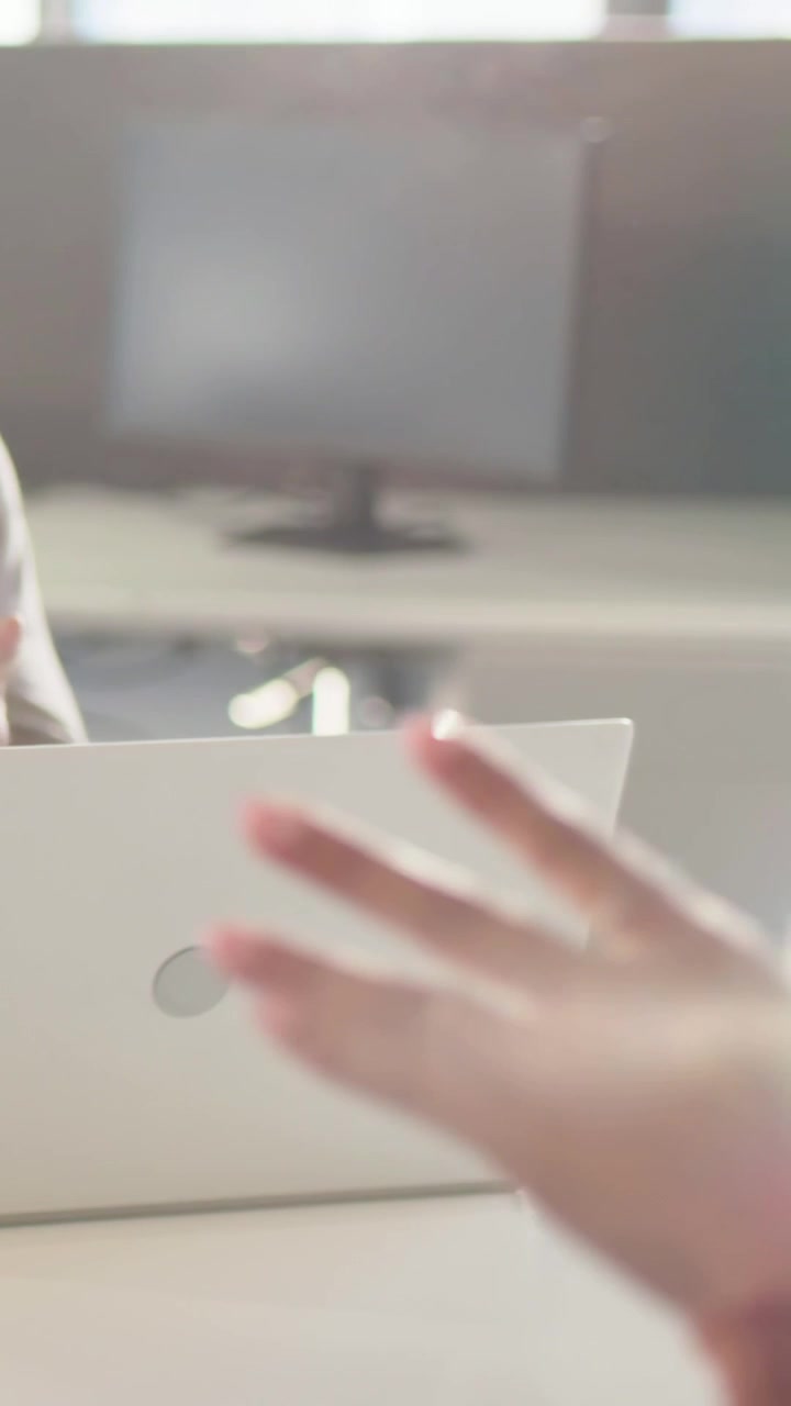Video verticale: Donna che inizia a parlare, gesticolando alla scrivania mentre discute di lavoro con un laptop, spazio per il testo