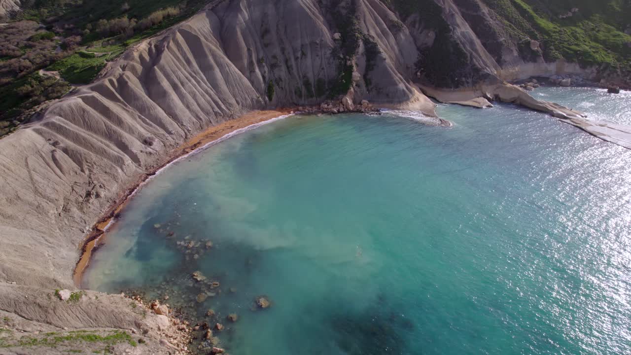 Video con drone che vola vicino a una baia rocciosa a Malta con acqua blu cristallina