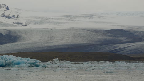 Glacier-Lagoon-in-Jökulsárlón,-Iceland,-featuring-glaciers-floating-in-icy-waters-with-snowy-mountains-in-the-background