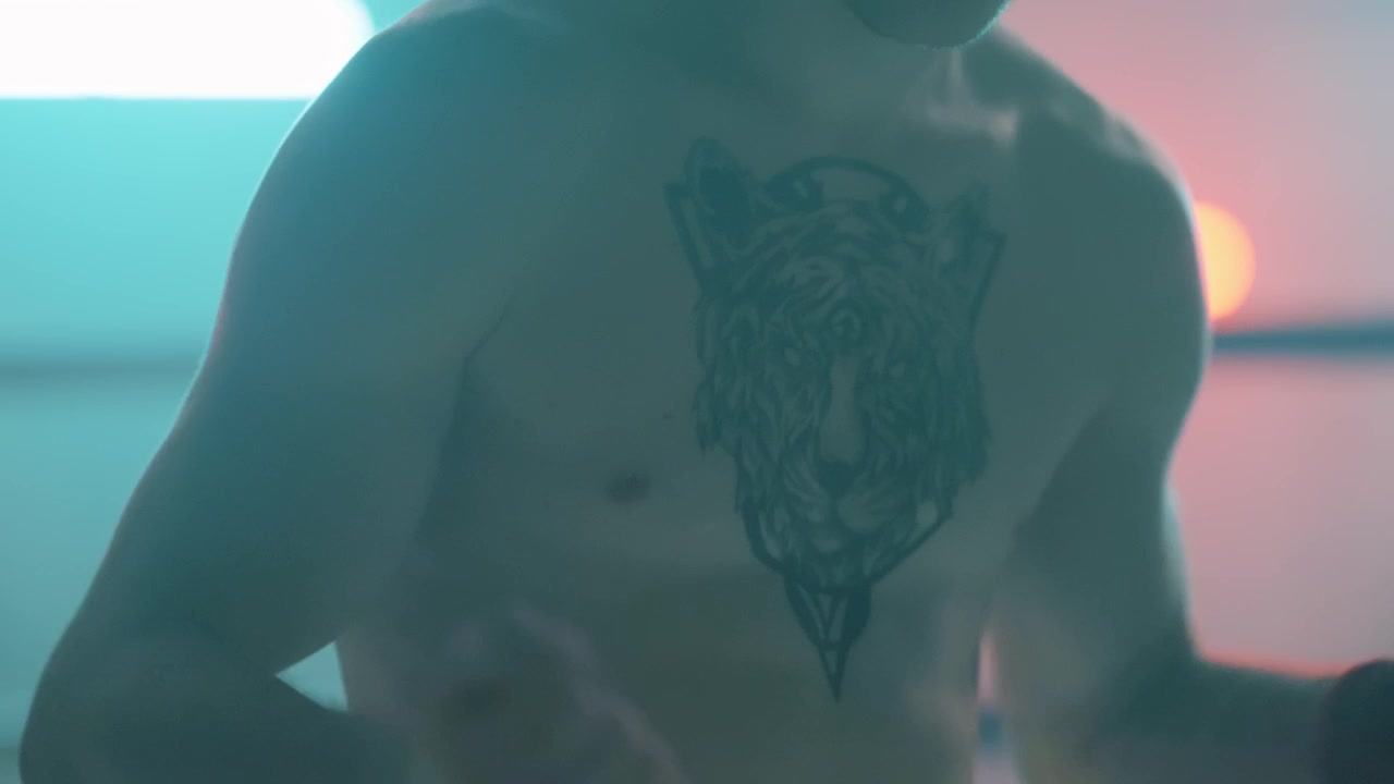 Uomo a torso nudo con tatuaggio di tigre sotto luci al neon drammatiche