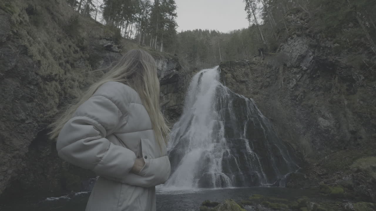 Woman admiring a waterfall in a forest