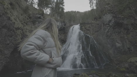 woman admiring a waterfall in a forest