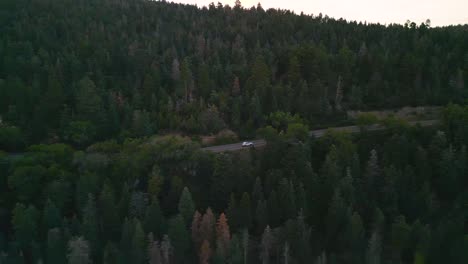 Luftaufnahme-Eines-Weißen-Autos-Auf-Einer-Ländlichen-Landstraße-In-Einem-Bunten-Wald,-Drohnenaufnahme-Verfolgend