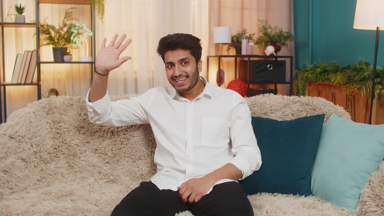 Indian young man smiling waving hand at camera greeting warmly friendly communication video call