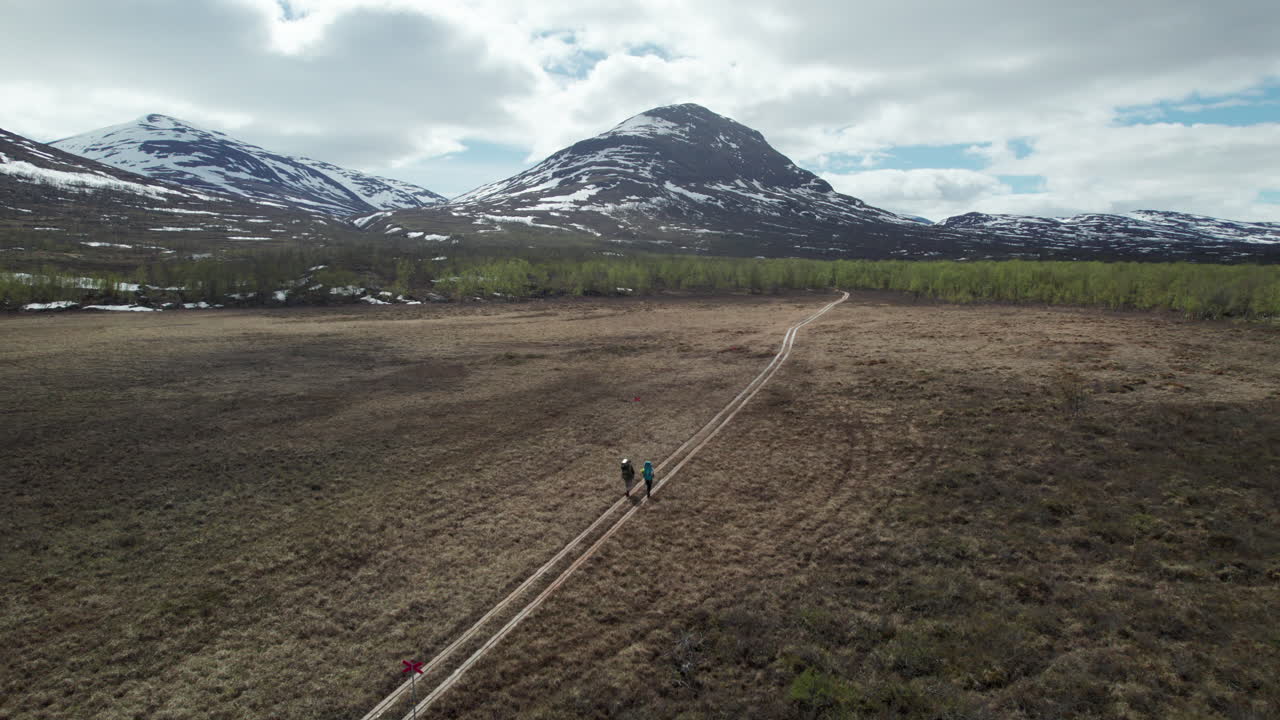 Young Couple Hiking on the Kungsleden in the Abisko National Park, Super Wide Drone Shot of Hikers from Behind in a Serene Mountain Swedish Landscape