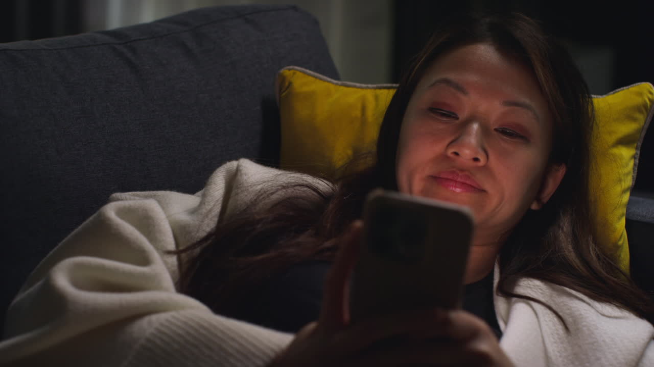 primer plano de una mujer pasando la noche en casa acostada en el sofá con el teléfono móvil desplazándose por internet o las redes sociales 3