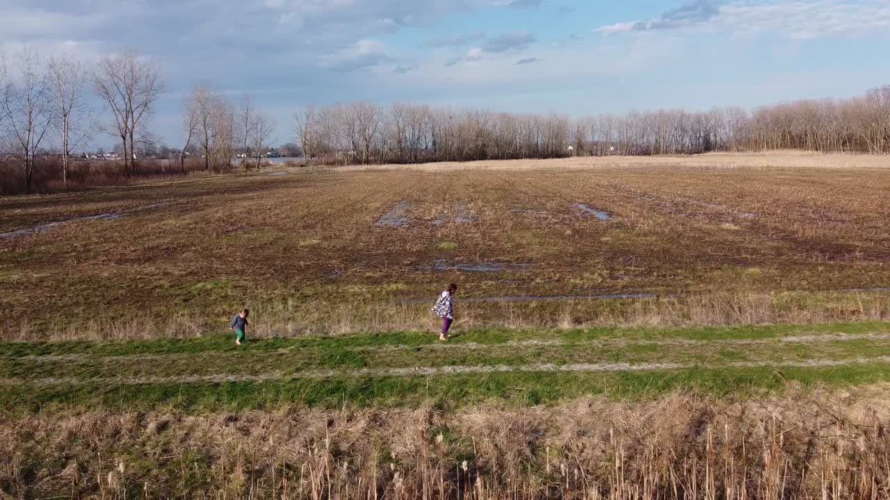 A Toddler Runs To His Sister Walking On The Pathway At  The Field In Monroe, Michigan On A Hot Sunny Day - Wide Shot