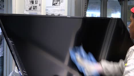 worker cleaning an lcd screen inside a factory