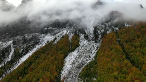 fog covers the high peak of the mountain and colorful forest in the idyllic alps of albania