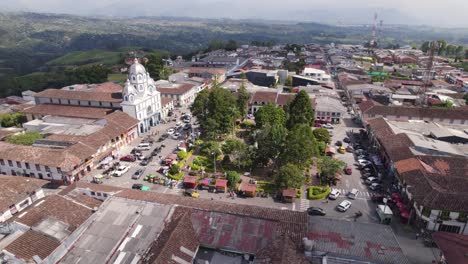 Rush-hour-around-Park-in-remote-village-Filandia-in-Colombia,-aerial-orbit