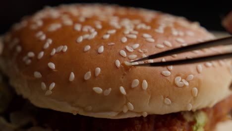 selecting individual tiny sesame seeds, fried chicken burger, slow-mo