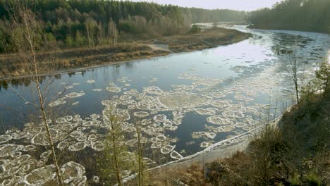 ice chunks going slow river down stream in sunny winter day