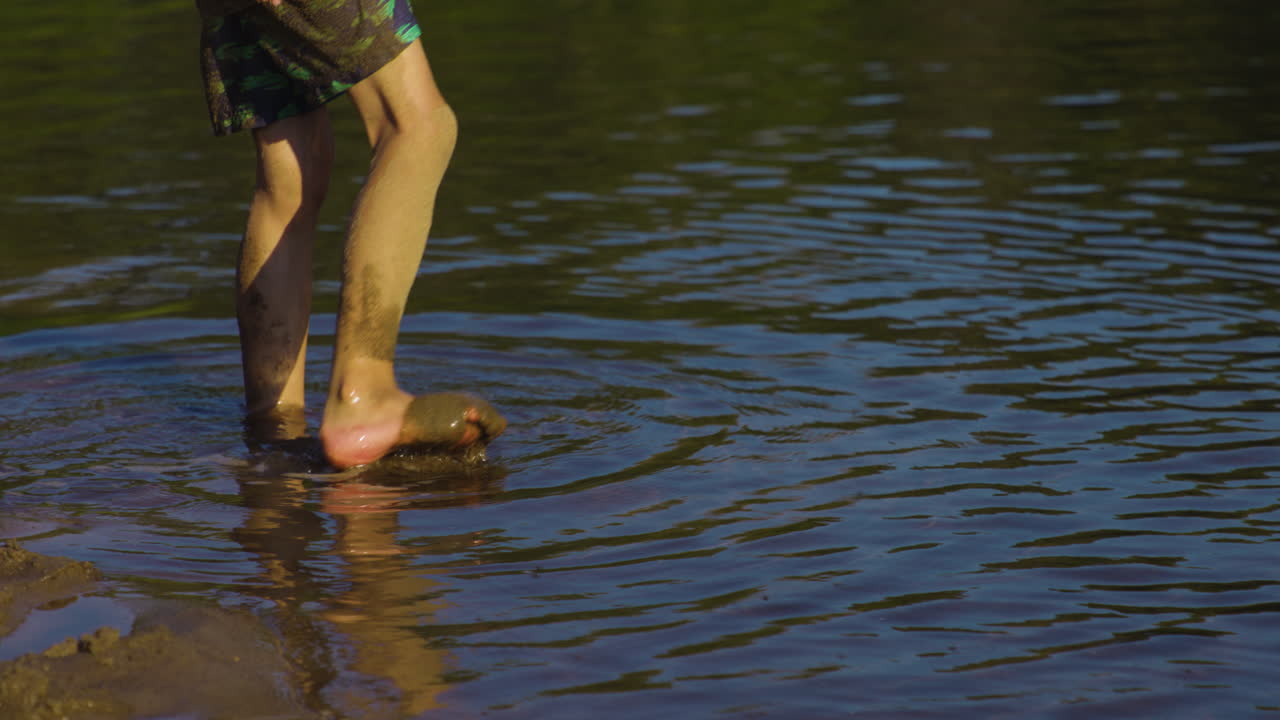 Little Boy Walking In The Shallow Water Of A Lake - close up
