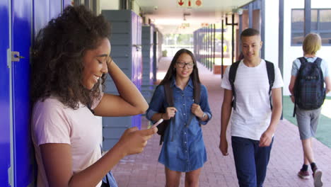 three teenage friends talk in school corridor, slow motion