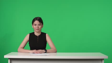woman news anchor sitting at a table in a news studio