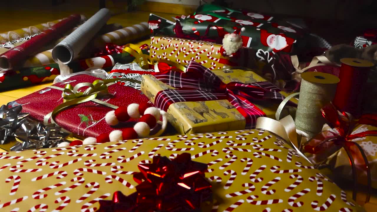 imágenes panorámicas sobre regalos de navidad bien envueltos y regalos con papel de envolver de colores y bastones de caramelo que están en un piso de madera bajo un árbol de navidad. rollos de papel de envoltar en el fondo.